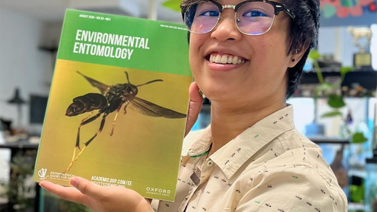 UC Davis alumna RJ Millena, doctoral candidate at the Richard Gilder Graduate School, American Museum of Natural History, holds the August issue of the journal 'Environmental Entomology."  Her research made the cover. (Photo by Lohit Garikipati)