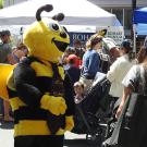 A costumed honey bee weaves through the crowd, as a little boy looks in awe, in this 2022 photo of the California Honey Festival. Inside the costume: Wendy Mather, co-program manager of the UC Davis-based California Master Beekeeper Program. (Photo by Kathy Keatley Garvey)