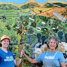UC Davis distinguished professor emerita Diane Ullman (right) and assistant professor Emily Meineke, both entomologists an artists, exult following the 2023 completion of their ceramic-mosaic mural, “The Secret Life of Vineyards,” installed at the Mathaiasson Winery on Dry Creek Road, Napa. It depicts more than 80 arthropods (insects, spiders and centipedes), several bird species, mammals (bobcat, deer, rabbits, squirrels, a pocket gopher), a gopher snake, mycorrhizal fungi and even earthworms, (Photo by Ga